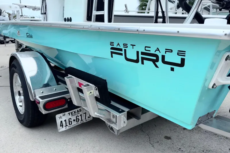 Slide: The Image of 2016 East Cape Fury boat on trailer, featuring sleek turquoise design and Texas license plate. - 7