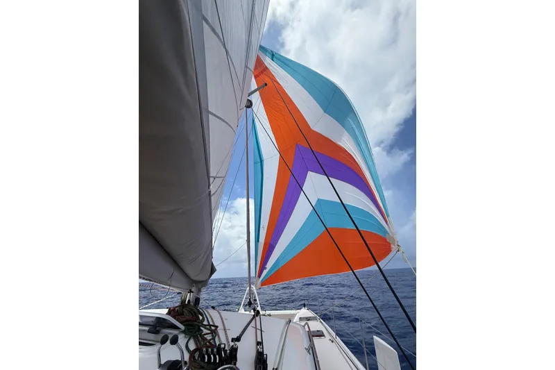 Slide: The Image of Outremer 51 sailboat with colorful spinnaker, 2022 model, sailing on open ocean under blue sky. - 2
