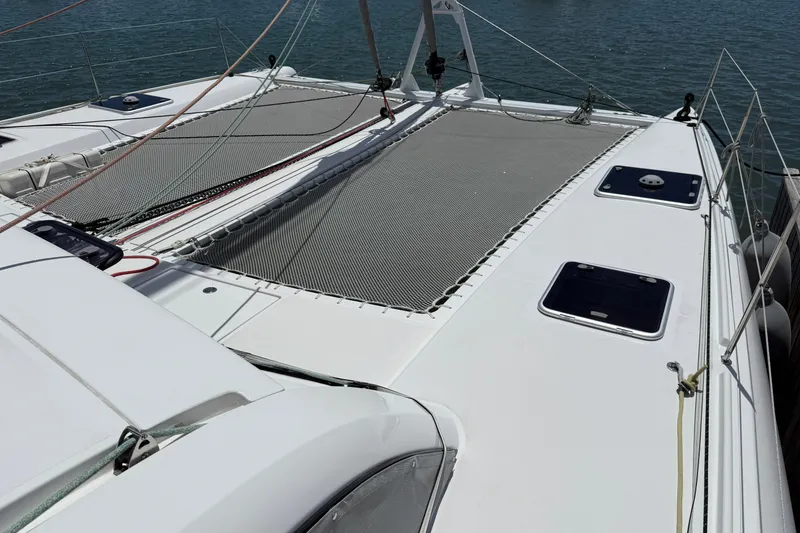 Slide: The Image of 2022 Outremer 51 catamaran deck with netting, hatches, and rigging on calm water. - 4