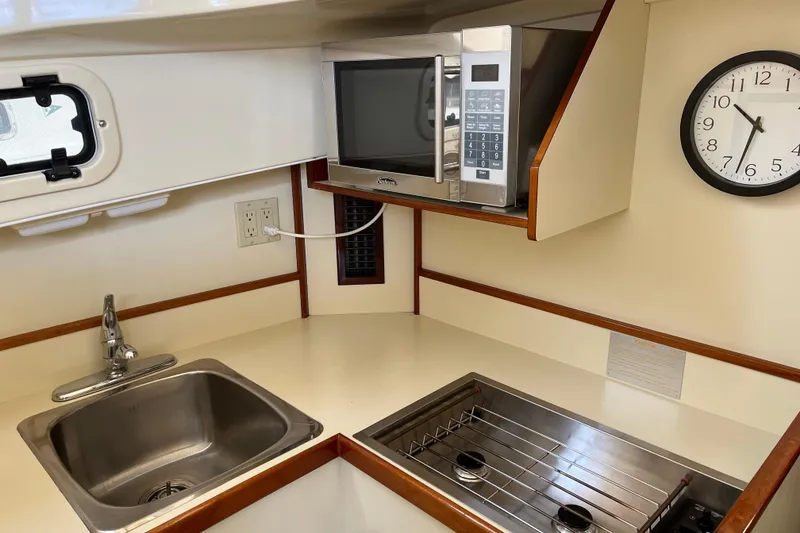 Slide: The Image of 2005 Camano Trawler kitchen with sink, microwave, stove, and wall clock. - 13