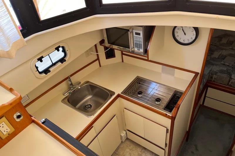 Slide: The Image of 2005 Camano Trawler kitchen with sink, stove, microwave, and clock. - 14