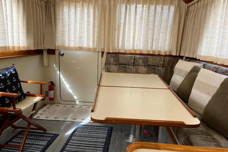 Slide: The Image of Interior of a 2005 Camano Trawler with dining area, cushioned seating, and nautical decor. - 15