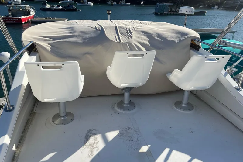 Slide: The Image of Three white seats on a 2005 Camano Trawler boat deck, overlooking the water. - 39