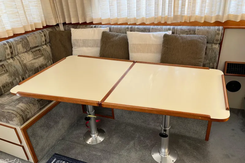 Slide: The Image of 2005 Camano Trawler interior with a foldable dining table and cushioned seating. - 9