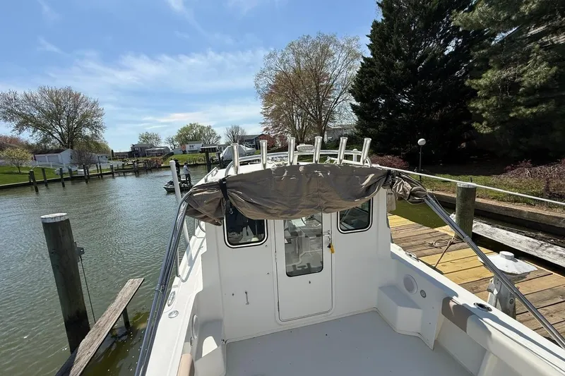 Slide: The Image of 2019 Parker 2150 boat docked by a scenic waterfront with trees and clear skies. - 2