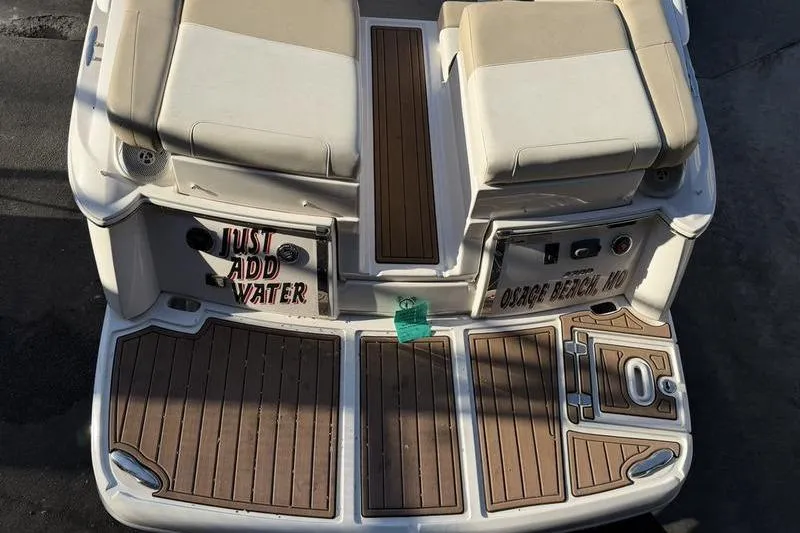 Slide: The Image of 2014 Regal 2700 ES Bowrider boat stern with teak flooring and cushioned seats. - 28