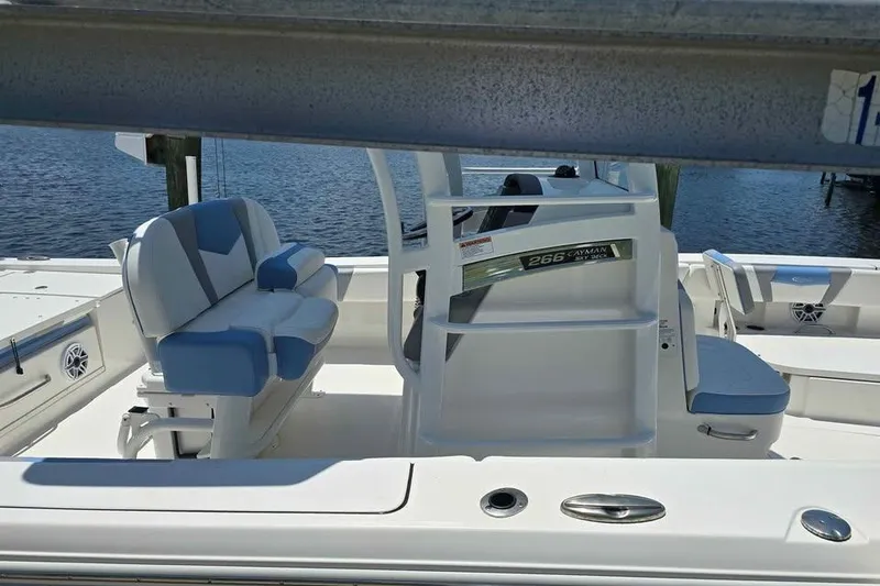 Slide: The Image of 2023 Robalo 266 Cayman SD boat interior with seating and helm, docked by the water. - 10