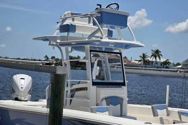 Slide: The Image of 2023 Robalo 266 Cayman SD boat docked by a scenic waterfront. - 2