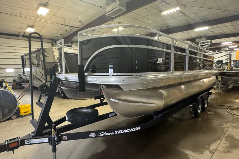 The Image of 2026 Sun Tracker Fishin' Barge 20 DLX pontoon boat in indoor storage. - 1