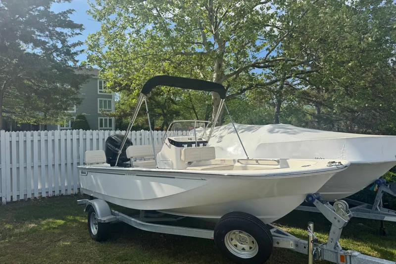 Slide: The Image of 2026 Boston Whaler 170 Montauk boat on trailer, parked outdoors near white fence. - 30
