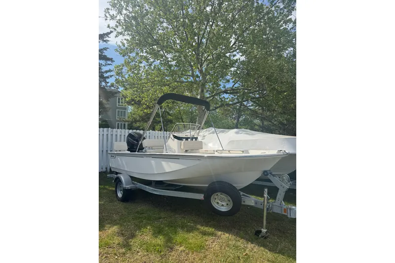 Slide: The Image of 2026 Boston Whaler 170 Montauk boat on trailer, parked outdoors near white fence. - 31