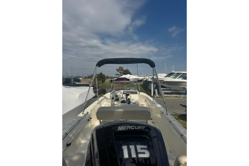 Slide: The Image of 2026 Boston Whaler 170 Montauk boat with Mercury 115 engine, docked under a blue sky. - 35