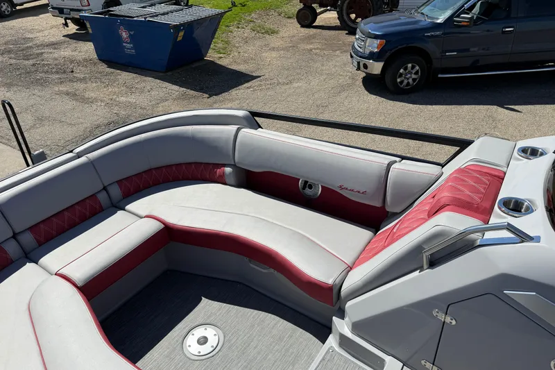 Slide: The Image of 2022 Bennington R 24 Quad Bench Bowrider with red and gray seating in a parking area. - 11