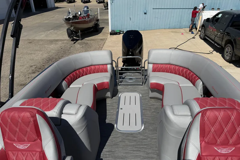 Slide: The Image of 2022 Bennington R 24 Quad Bench Bowrider with red and gray seating in a marina setting. - 16