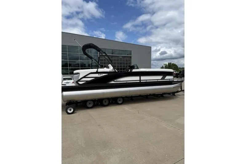 Slide: The Image of 2025 Bennington 26 MFB-SPT pontoon boat on trailer, parked outside a modern building. - 3