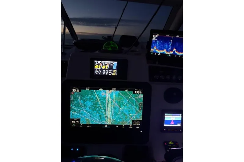 Slide: The Image of Dashboard of a 2015 Edgewater 280CX Crossover boat with navigation screens at dusk. - 11