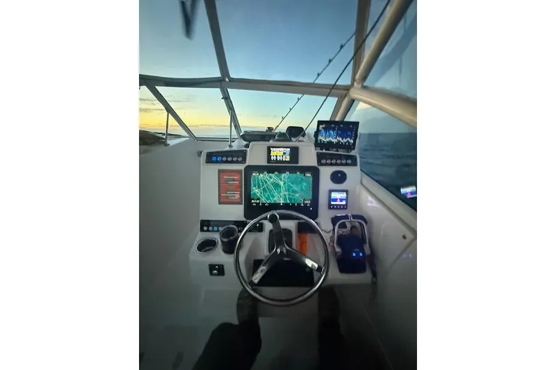 Slide: The Image of Cockpit view of 2015 Edgewater 280CX Crossover boat at sunset, featuring navigation equipment. - 12