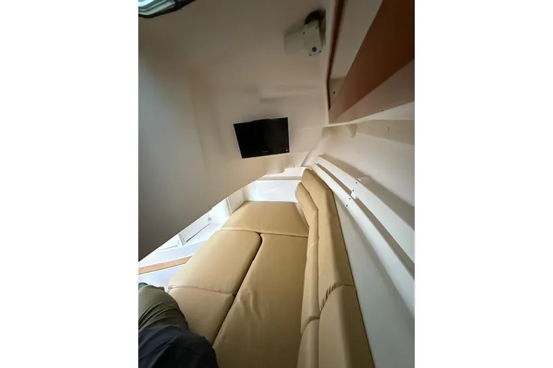 Slide: The Image of Interior of 2015 Edgewater 280CX Crossover boat with beige seating and wall-mounted TV. - 13