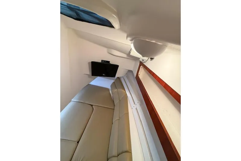 Slide: The Image of Interior cabin of 2015 Edgewater 280CX Crossover boat with beige seating and TV. - 14