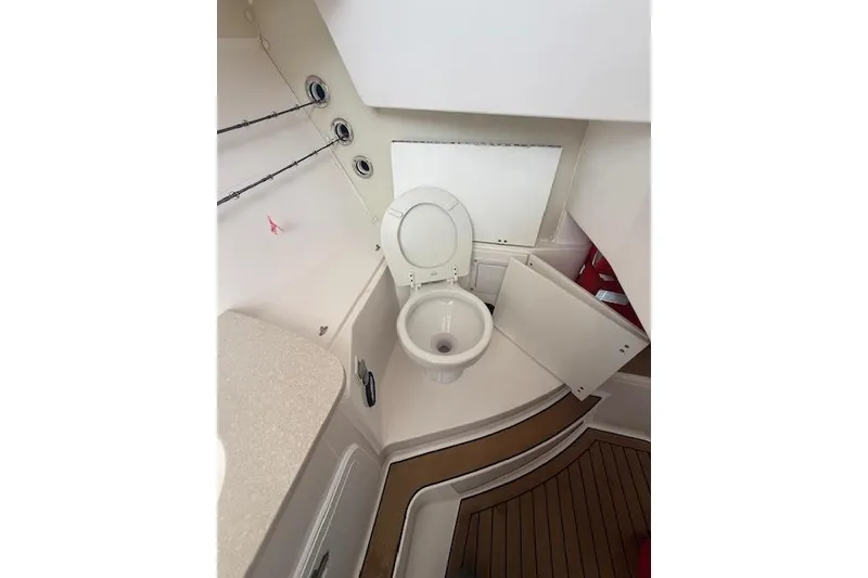 Slide: The Image of Interior of 2015 Edgewater 280CX Crossover boat featuring a compact marine toilet. - 17