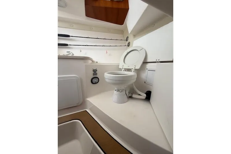 Slide: The Image of Interior of 2015 Edgewater 280CX Crossover boat featuring a compact marine toilet. - 18