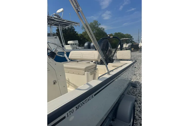 Slide: The Image of 2026 Boston Whaler 170 Montauk boat on gravel lot under blue sky. - 30