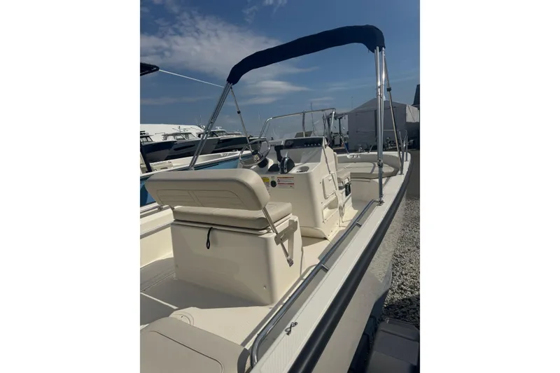 Slide: The Image of 2026 Boston Whaler 170 Montauk boat with canopy, docked under clear sky. - 33