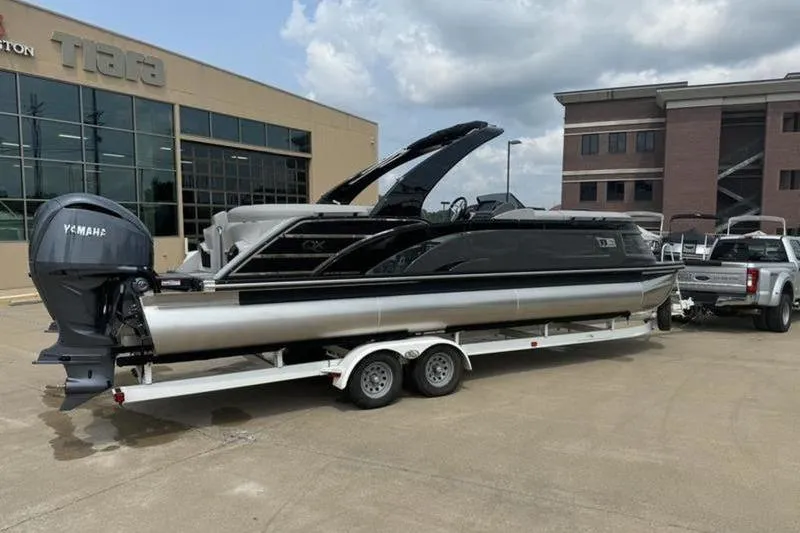 The Image of 2025 Bennington 27 QXFBAT2 pontoon boat on trailer, parked outside dealership. - 1