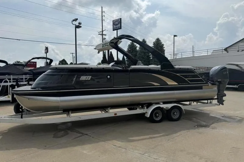 Slide: The Image of 2025 Bennington 27 QXFBAT2 pontoon boat on a trailer, parked outdoors. - 7