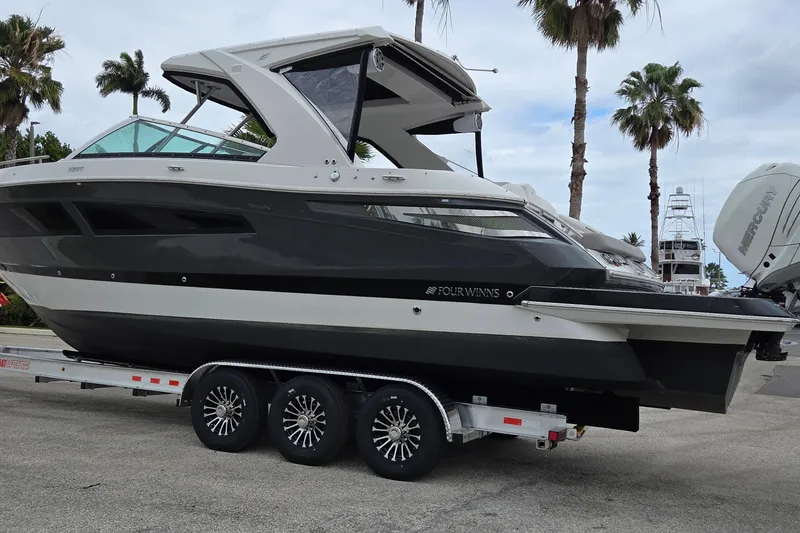 Slide: The Image of 2019 Four Winns H350 OB boat on trailer, parked with palm trees in background. - 2