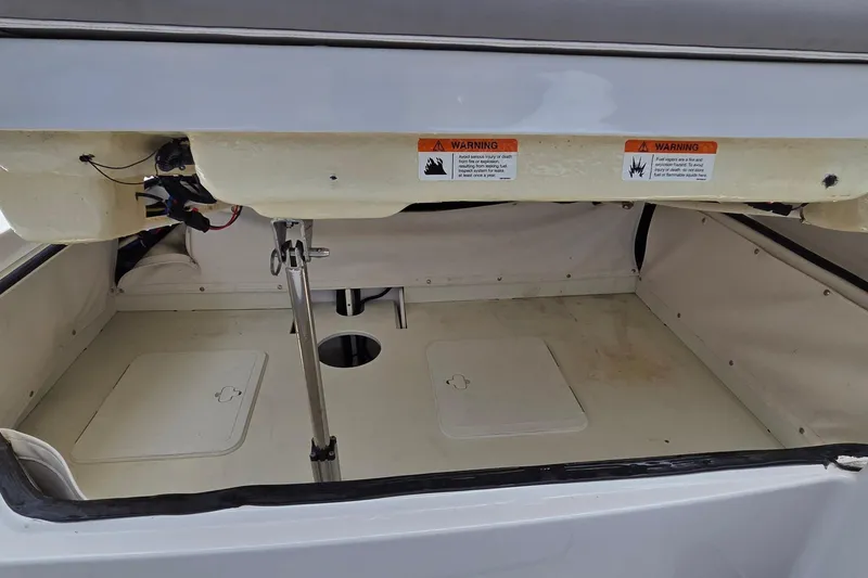 Slide: The Image of 2019 Four Winns H350 OB boat storage compartment with warning labels and hydraulic lift. - 24