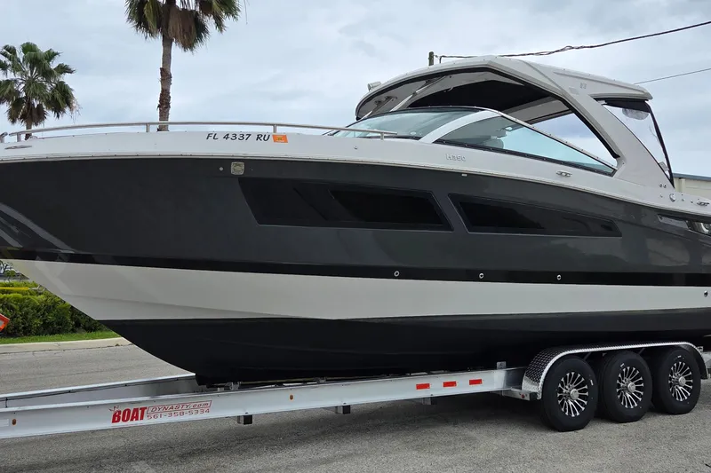 Slide: The Image of 2019 Four Winns H350 OB boat on trailer, sleek design, parked near palm trees. - 3
