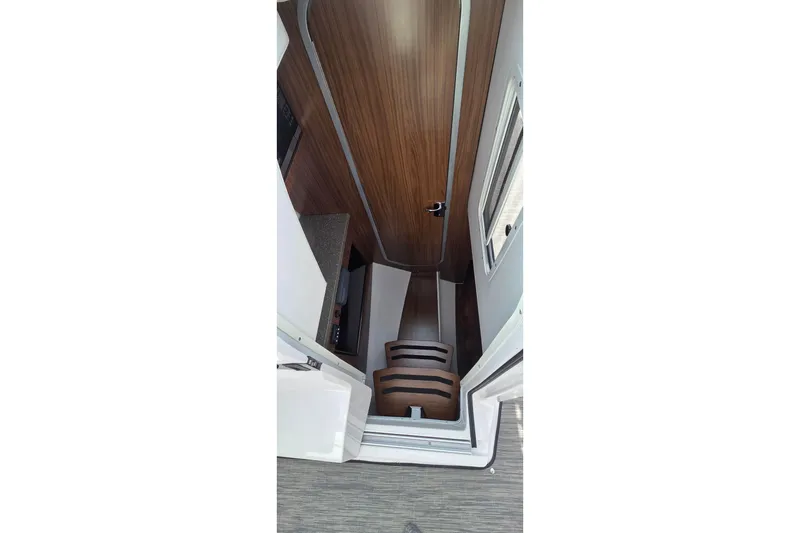 Slide: The Image of Interior stairs of 2019 Four Winns H350 OB boat, featuring wood paneling and compact design. - 45