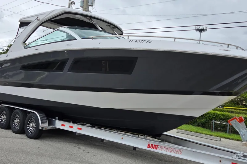 Slide: The Image of 2019 Four Winns H350 OB boat on trailer, sleek design, parked outdoors. - 5