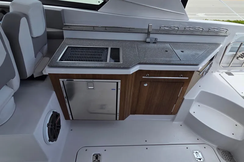 Slide: The Image of 2019 Four Winns H350 OB boat interior with kitchenette, featuring sink, grill, and storage. - 9