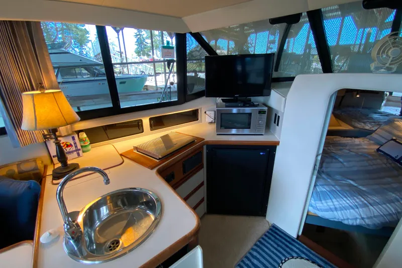 Slide: The Image of Interior of 1991 Carver 28 Command Bridge with kitchenette, sink, and cozy sleeping area. - 10