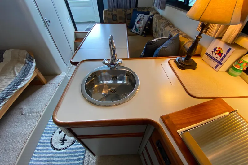 Slide: The Image of Interior of 1991 Carver 28 Command Bridge with sink, seating, and cozy decor. - 12