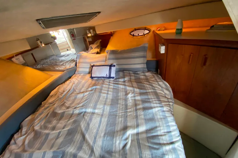 Slide: The Image of Cozy cabin interior of 1991 Carver 28 Command Bridge with striped bedding and wooden cabinets. - 19