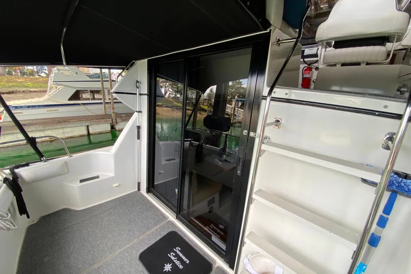 Slide: The Image of 1991 Carver 28 Command Bridge boat interior with seating, storage, and glass door. - 34