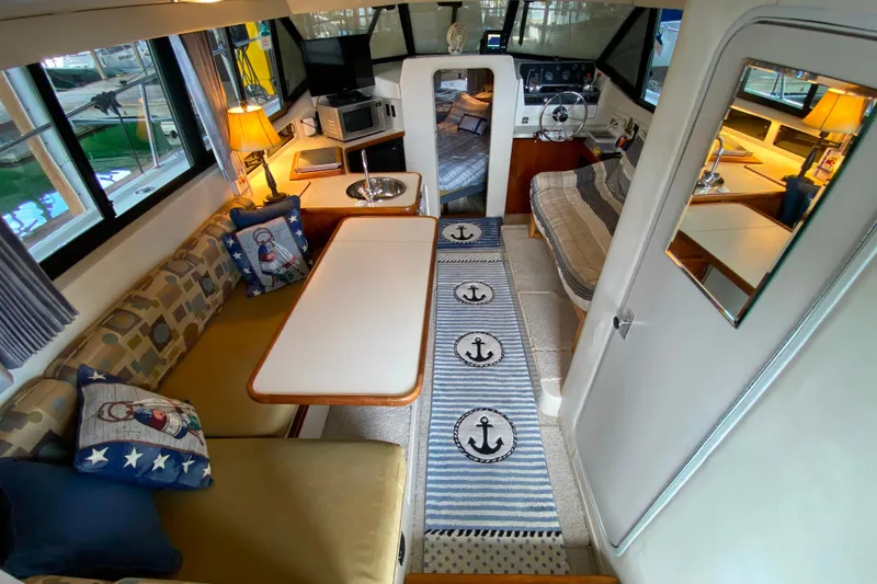 Slide: The Image of Interior of 1991 Carver 28 Command Bridge with cozy seating, nautical decor, and helm view. - 7