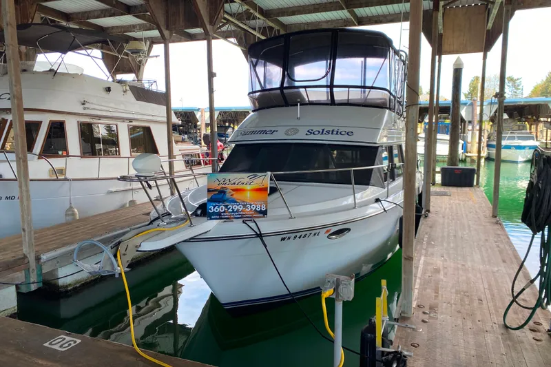 Slide: The Image of 1991 Carver 28 Command Bridge docked in marina, featuring "Solstice" name on bow. - 70