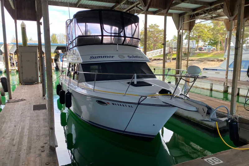 Slide: The Image of 1991 Carver 28 Command Bridge docked in a marina under a covered slip. - 71