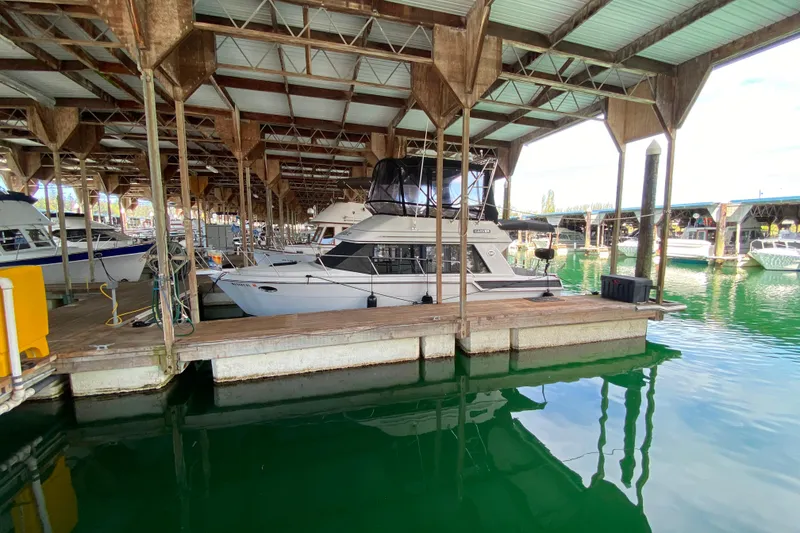 Slide: The Image of 1991 Carver 28 Command Bridge docked in a covered marina, surrounded by calm water. - 72