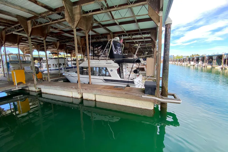 Slide: The Image of 1991 Carver 28 Command Bridge docked in a covered marina with calm water. - 74