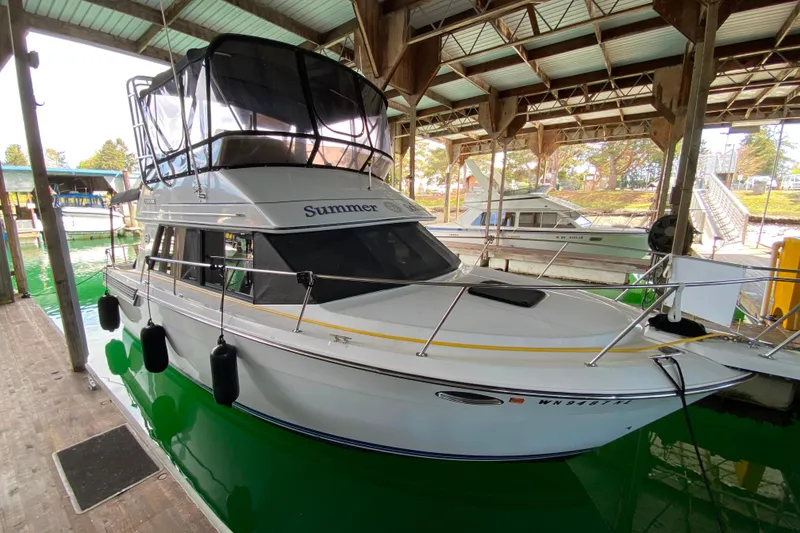 Slide: The Image of 1991 Carver 28 Command Bridge docked in a covered marina, named "Summer." - 75