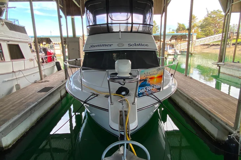 Slide: The Image of 1991 Carver 28 Command Bridge docked, named "Summer Solstice," in a marina setting. - 76