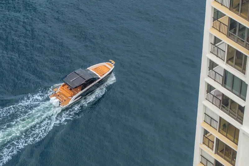 Slide: The Image of Aerial view of Hanover 387 boat cruising near a waterfront building, 2026 model. - 24