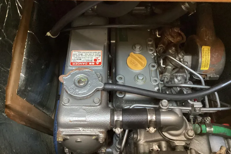 Slide: The Image of Engine compartment of a 1999 Hunter 340 sailboat, showcasing mechanical components and warning labels. - 20