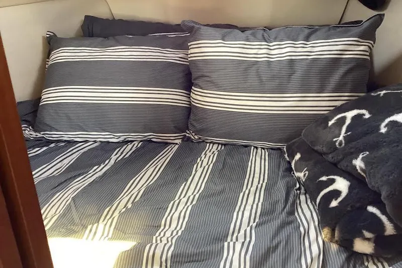 Slide: The Image of Cozy cabin bed in 1999 Hunter 340 sailboat with striped bedding and anchor-themed blanket. - 21