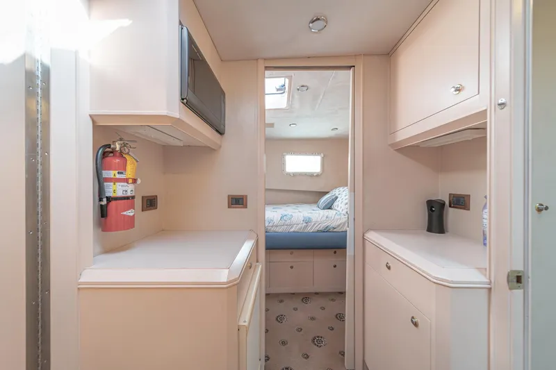 Slide: The Image of 1995 Nordlund Cockpit Motor Yacht interior with bedroom, cabinets, and fire extinguisher. - 48